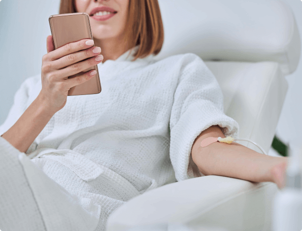 Woman holding phone while having a IV drip